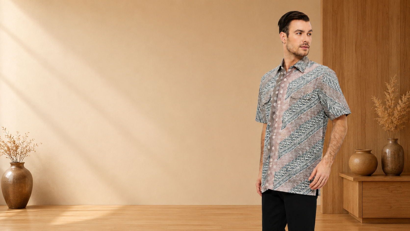 Model wearing an Arya Putra Batik parang short-sleeve shirt in a warm minimalist room